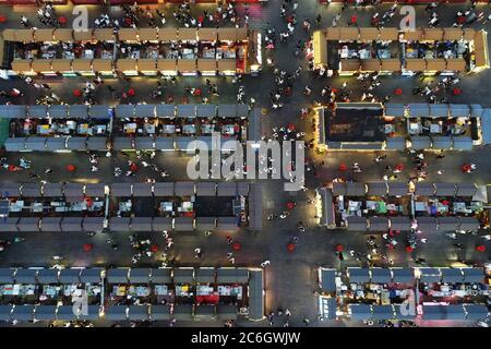 An aerial view of tourists wandering among and buying food from snack bars at Xingshun International Night Market, Asia's largest night market, Shenya Stock Photo