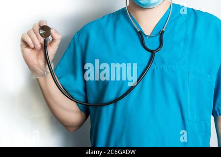 Male doctor in blue coat show stethoscope on white - cropped image.  Stock Photo