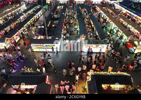 An aerial view of tourists wandering among and buying food from snack bars at Xingshun International Night Market, Asia's largest night market, Shenya Stock Photo