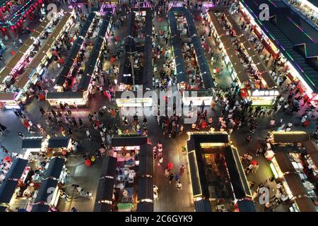 An aerial view of tourists wandering among and buying food from snack bars at Xingshun International Night Market, Asia's largest night market, Shenya Stock Photo