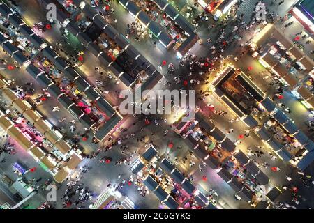 An aerial view of tourists wandering among and buying food from snack bars at Xingshun International Night Market, Asia's largest night market, Shenya Stock Photo