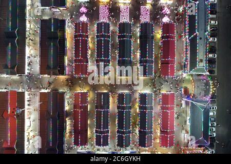 An aerial view of tourists wandering among and buying food from snack bars at Xingshun International Night Market, Asia's largest night market, Shenya Stock Photo