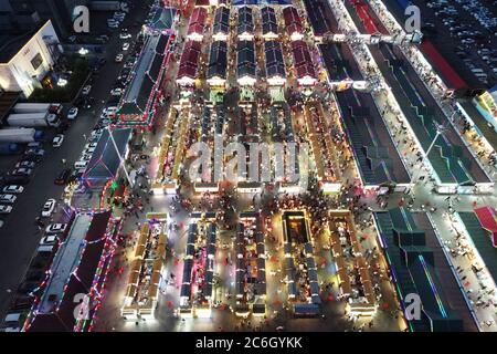 An aerial view of tourists wandering among and buying food from snack bars at Xingshun International Night Market, Asia's largest night market, Shenya Stock Photo