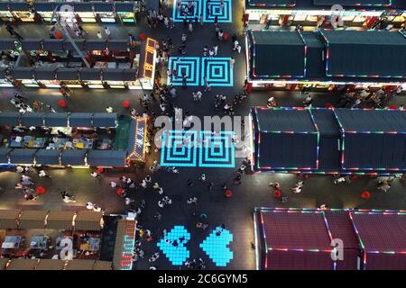 An aerial view of tourists wandering among and buying food from snack bars at Xingshun International Night Market, Asia's largest night market, Shenya Stock Photo