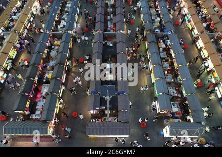 An aerial view of tourists wandering among and buying food from snack bars at Xingshun International Night Market, Asia's largest night market, Shenya Stock Photo