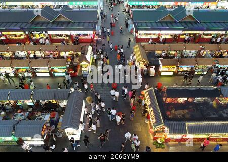 An aerial view of tourists wandering among and buying food from snack bars at Xingshun International Night Market, Asia's largest night market, Shenya Stock Photo