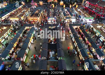 An aerial view of tourists wandering among and buying food from snack bars at Xingshun International Night Market, Asia's largest night market, Shenya Stock Photo