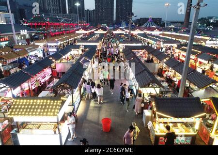 An aerial view of tourists wandering among and buying food from snack bars at Xingshun International Night Market, Asia's largest night market, Shenya Stock Photo