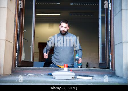 Glasgow, Scotland, UK. 10th July, 2020. Pictured: A joiner works on the windows on the City Chambers in George Square. Since the lockdown prevented construction and renovations being done, since the lockdown has eased, joiners and trades can now go back to work to get essential maintenance done. Credit: Colin Fisher/Alamy Live News Stock Photo