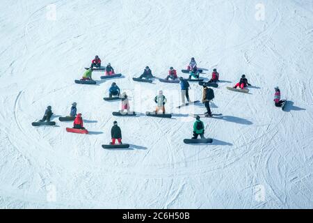 Lots of skiers and snowboarders have a rest on a slope at ski resort Stock Photo