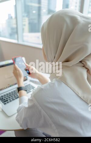 muslim women doing work with her gadget Stock Photo