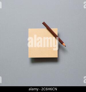 Brown kraft memo pad, empty paper with colored pencil on gray background. top view, copy space Stock Photo