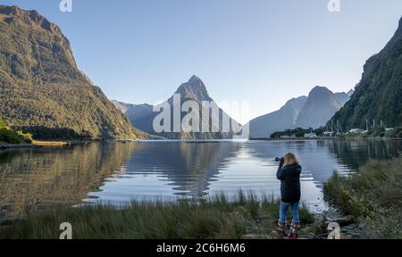 Asian woman looking at view with beautiful scenic of milford sound in fiordland national park new zealand. Stock Photo