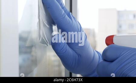 Close Up Man Hands with Protection Gloves Cleaning a Window Using Sprayed Liquid Disinfecting Against Viruses Contamination Stock Photo