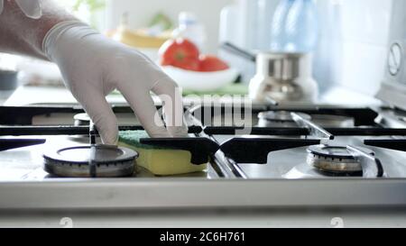 Busy Person in the Kitchen Wearing Gloves Cleans with Solution the Cooker Stove. Stock Photo