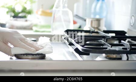 Busy Person in the Kitchen Wearing Gloves Cleans with Solution the Cooker Stove. Stock Photo