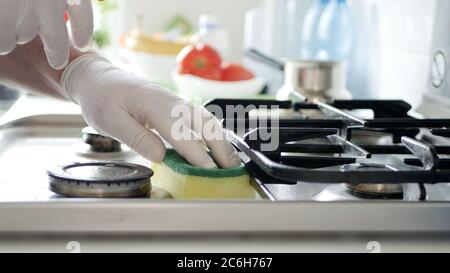 Busy Person in the Kitchen Wearing Gloves Cleans with Solution the Cooker Stove. Stock Photo