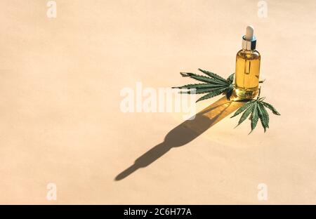 Glass bottle and dropper CBD OIL, THC tincture and cannabis leafs on pastel background. Laboratory Production of cosmetics with CBD oil. Stock Photo