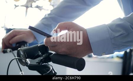 Man on the Bicycle Text Using a Cellphone and Access Network Online Applications, Biker Typing a Message on Mobile Stock Photo