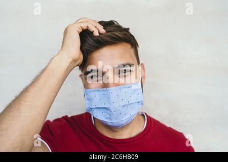 Young man wearing face mask portrait - Latin boy using protective facemask for preventing spread of corona virus Stock Photo