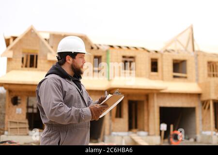 Builder drawing plan in notebook at construction site. Stock Photo