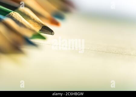Shallow focus view of a close-up image of new colouring pencils seen on blank writing paper. Detail of some of the colouring pencil tips is evident. Stock Photo