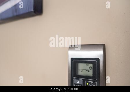 Close-up view of a modern, LCD air-con keyboard and display seen in a modern apartment. Seen near modern, abstract art hanging of the same wall. Stock Photo