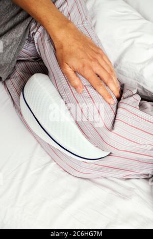 https://l450v.alamy.com/450v/2c6hg7m/closeup-of-a-caucasian-man-wearing-striped-pajama-pants-using-an-anatomical-cushion-between-his-legs-while-is-lying-on-a-bed-set-with-white-bedsheet-2c6hg7m.jpg