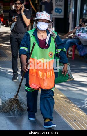 Street cleaner wearing face mask and high visibility clothes during covid 19 pandemic, Bangkok, Thailand Stock Photo