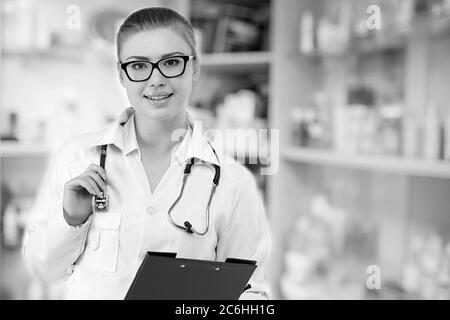 Young pretty female doctor in white uniform on blurry medicine cabinet and store medicine and pharmacy drugstore for background Stock Photo