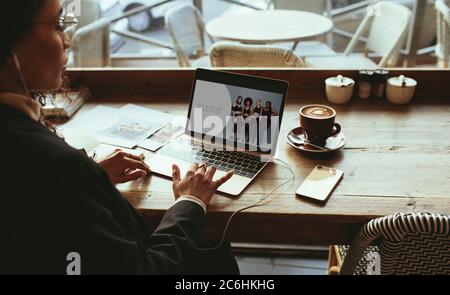 Businesswoman working on her laptop at a cafe. Woman sitting at a coffee shop preparing an advertisement campaign on her laptop computer. Stock Photo