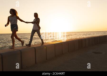 Caucasian couple enjoying their time on a promenade during a sunset Stock Photo