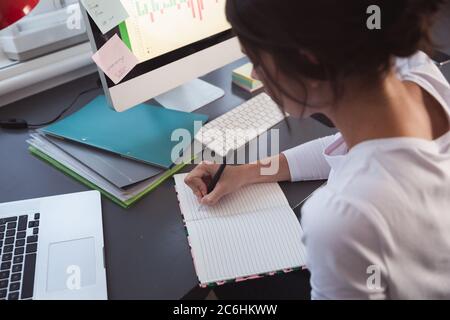 Woman taking notes while sitting on her desk Stock Photo