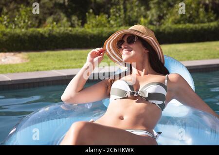 Woman floating on a inflatable ring in the swimming pool Stock Photo