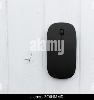 Black computer mouse on a wooden background, top view Stock Photo