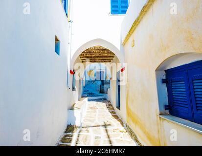 Scenic view of an old narrow stone paved lane with white houses, blue doors and an arch, Lefkes, Greece Stock Photo