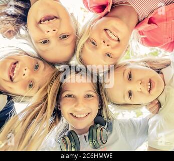 Shot from below of happy smiling little girls standing in circle, close-up Stock Photo