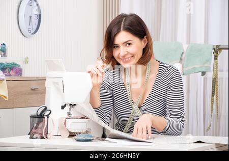 Happy tailor woman working with freshly made template with pencil and measure tape Stock Photo