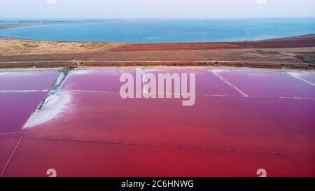 View from drone above the pink salty Genichesk lake, sand spit and blue sea at distance in Ukraine. Stock Photo