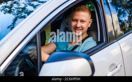 Young attractive man in white car, lookind at the camera Stock Photo