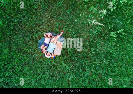 two little girls lying on a green grass, aerial top view Stock Photo
