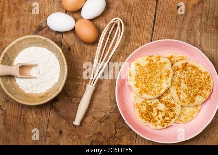Pancakes on a pink plate on a wooden table in a directly above view Stock Photo
