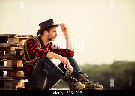 Let him ride a horse. wild west rodeo. Thoughtful man in hat drink whiskey. western cowboy. Vintage style man. Wild West retro cowboy. cowboy with lasso rope. Western. man checkered shirt on ranch. Stock Photo