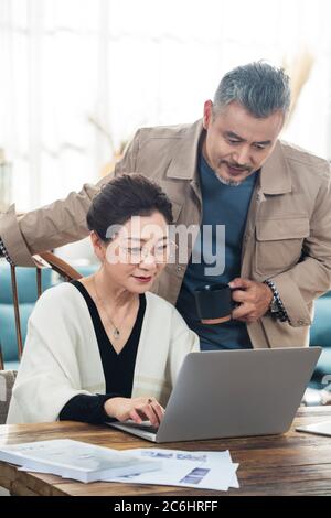 Happy old couple using laptop at home Stock Photo