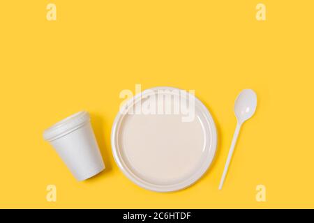 Disposable plastic white tableware set on a yellow background in a directly above view Stock Photo
