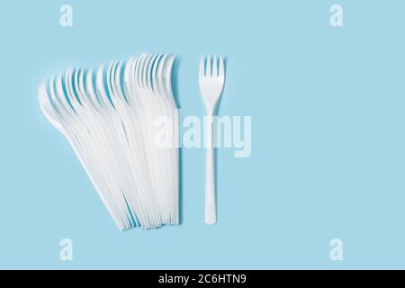 Disposable white plastic forks on a light blue background in a top view Stock Photo