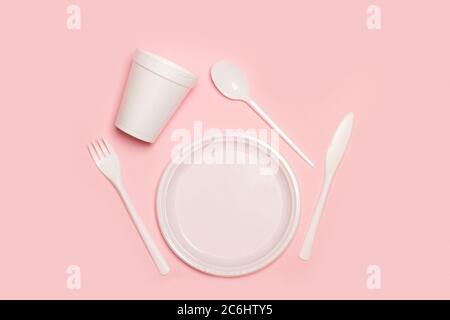 Disposable plastic white tableware set on a pink background in a top view Stock Photo