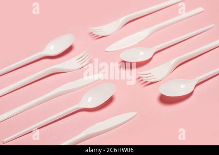 Disposable white plastic flatware on a pink background in a top view Stock Photo