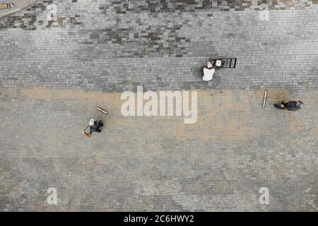 The masters lays paving stones. Sidewalk Repair. Road Workers Aerial View. Stock Photo