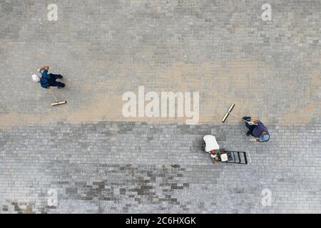 workers lay paving slabs top view Stock Photo